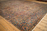 Angled view of a vintage Kerman carpet's corner, showing the intricate floral border and short pile.