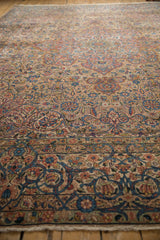 Detailed view across the short pile of a distressed Kerman carpet, focusing on its sprawling floral and vine pattern.