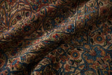 Detailed floral vines in sapphire blue and red on the draped pile of a vintage Kerman.