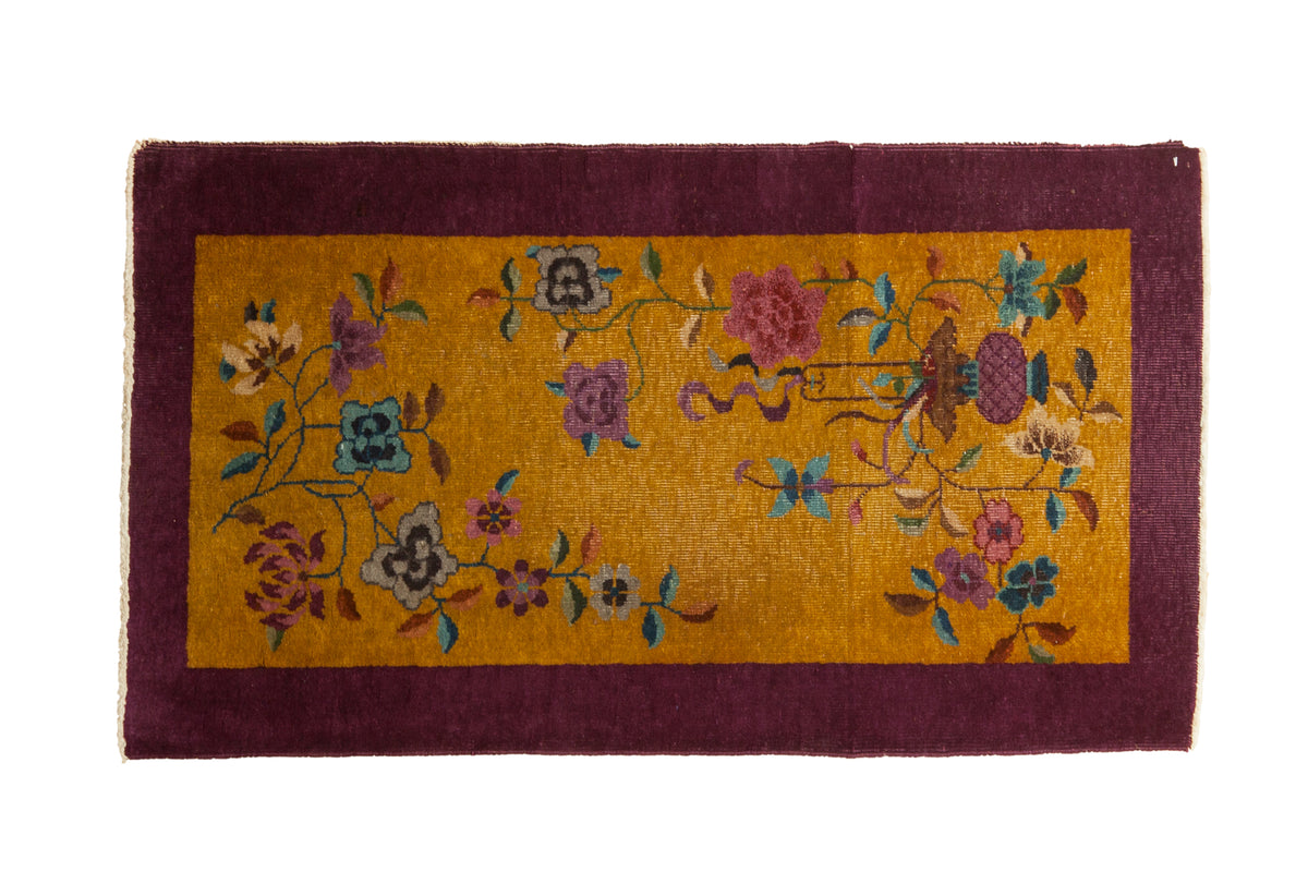 Vintage Nichols Art Deco rug with flowing florals on a gold field and a solid aubergine purple border.
