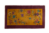 Vintage Nichols Art Deco rug with flowing florals on a gold field and a solid aubergine purple border.