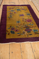 Perspective view of a vintage Nichols rug, showcasing its asymmetrical floral pattern and deep purple border.