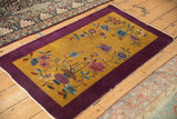 Vintage Nichols rug with asymmetrical floral vines on a gold field, seen from an angle.