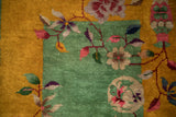 Detailed view of stylized Art Deco florals on the jade green wool pile next to a rich gold border.