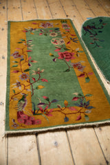 An angled view of the vintage Nichols rug's lush pile and botanical motifs on a green and gold ground.