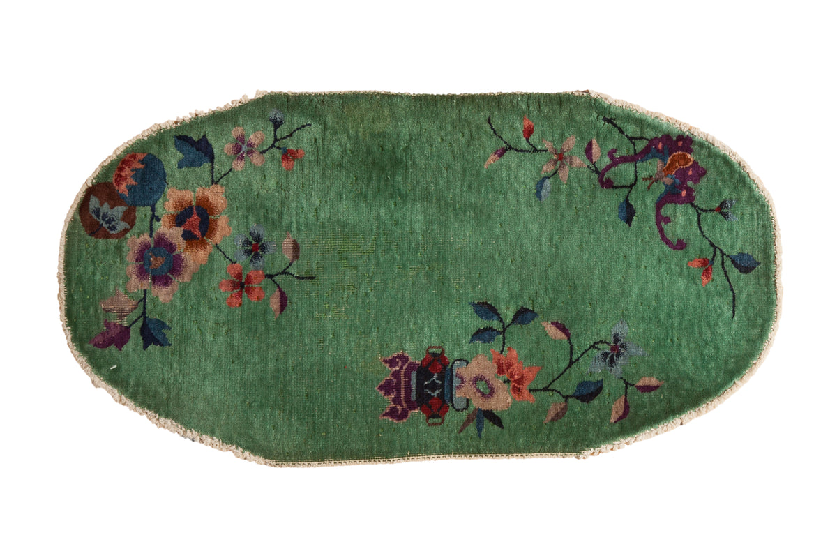 A vintage Nichols Art Deco rug with an oval shape, jade green field, and sparse floral motifs.