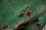 A fold in the jade green Nichols rug reveals dusty blue and pomegranate floral sprays.