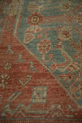 A stylized bird motif within the worn, ruby-red field of a vintage Malayer runner.