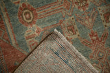 Corner of a distressed Persian rug showing the hand-knotted foundation and worn, low-pile texture.