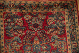 Dense cherry red field and navy blue floral sprays in vintage Sarouk rug corner.