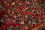 Rich cherry red pile with dense floral sprays in sapphire blue and jade green.