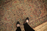 Antique Kerman rug's fluid, shield-like vinery pattern, rich reds, blues, and visible foundation.