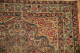 Antique Kerman rug corner with cochineal red floral border, sapphire blue vinery, and age-consistent wear.