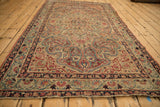 Antique Kerman rug corner, ivory field with cochineal red, navy curvilinear border and aged texture.