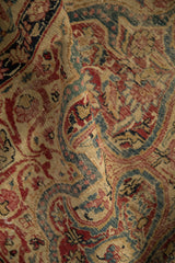 Antique Kerman rug detail: fluid vinery in ivory, cochineal red, sapphire blue, with wear.