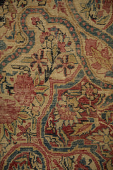 Antique Kerman rug detail: worn curvilinear vinery, cochineal red, sapphire blue, ivory tones, with exposed foundation.