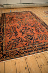 Transitional Sarouk rug detail: dusty rose field, speckled abrash, and dark navy floral motifs.