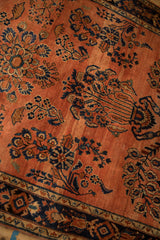 Terra cotta field with subtle speckled abrash and dark navy floral patterns.