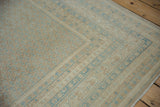 Corner of distressed Mir Sarouk rug with sky blue boteh patterns and thin borders.