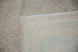 Distressed beige pile with sky blue botehs, showing wear, hand-knotted foundation and secured side.