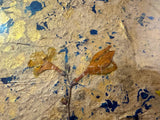 Textured detail of mixed media art with dried botanicals, gold accents, and blue paint.