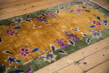 Stylized floral vinery on the gold field and celadon green border of a Nichols rug.