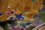 Folded Nichols Art Deco rug detail: gold pile, celadon green border, purple-blue blossoms.