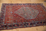Vintage Bijar rug corner with detailed Herati pattern, pomegranate red, sky blue, and navy border.