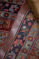 Vintage Bijar rug edge, secured with a dark leather strap and traditional Herati pattern.