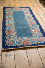 Fringed end of vintage Chinese Art Deco rug, featuring blush, apricot, celadon floral border.