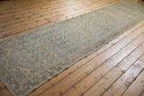 Distressed vintage Hamadan rug corner, pale blue henna plant motif, meandering vine border.