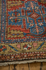 Antique Northwest Persian rug close-up: sapphire blue field, brick red serrated leaves, and ochre geometric border.