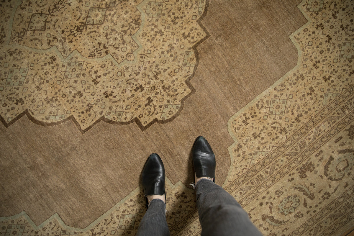 Distressed beige antique Tabriz carpet field, showing faint foundation and patterned scalloped spandrel.