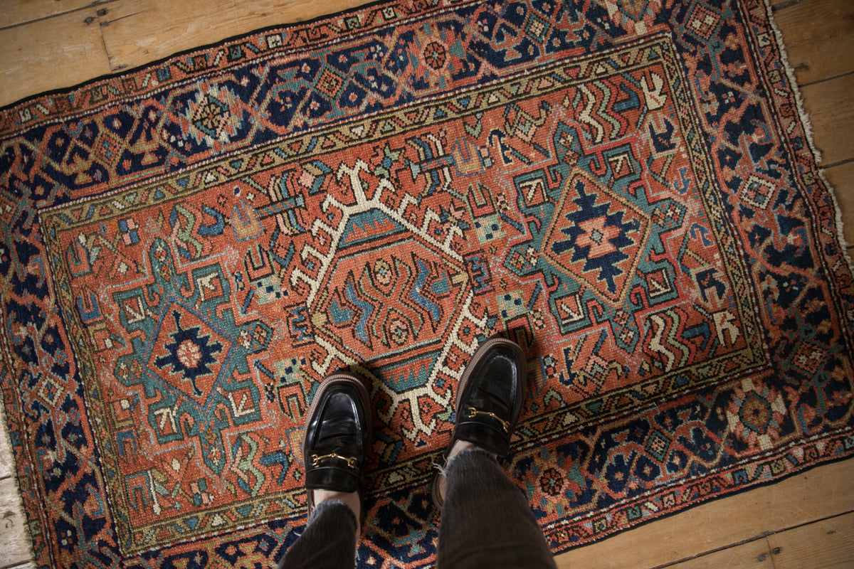 Vintage Karaja rug corner: navy geometric border, brick red field, meandering vine motifs.