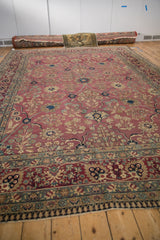 Antique Kerman rug border with blush red palmettes, dusty jade floral bells, and fringe.