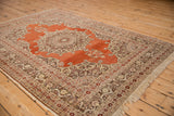 Angled view of an antique Haji Jalili Tabriz rug's handsome red-rust field and ornate border.