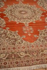 An angled perspective across the rust-red field toward the ornate medallion of an antique Tabriz rug.