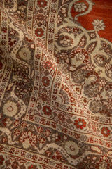 Close-up of the antique Haji Jalili rug's silvery bronze border with lotus and serpent motifs.
