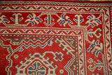 Geometric corner spandrel in ivory, blue, and mallard green on the distressed red Oushak carpet.