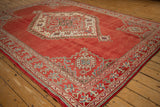 Geometric corner spandrel and border in ivory, blue, and green on a distressed red Oushak carpet.