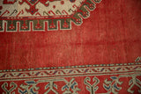 Hand-knotted pile and distressed texture on the cherry red field of a vintage Oushak carpet.
