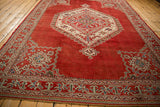 Angled view of a distressed Oushak carpet's large geometric medallion and rich cherry red field.
