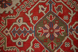 Distressed hand-knotted pile showing geometric motifs in red, blue, and mallard green.