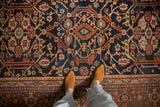 Close-up view of the low pile texture and geometric scrolling vinery of a vintage Mahal carpet.