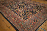 Corner view of a vintage Mahal carpet's terracotta rust border and intricate navy floral field.