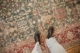 Low pile texture of a distressed Tabriz carpet with a floral lattice design in green, red, and sand tones.