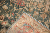 Lifted corner of a distressed Tabriz carpet reveals the hand-knotted foundation and worn pile.