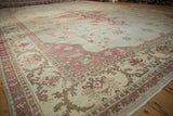Angled view across the distressed ivory pile and raspberry-red border of a vintage Amritsar carpet.