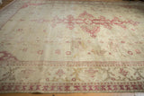 Textural surface of a distressed Amritsar carpet with visible knot heads and faded red motifs.