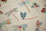 Embroidered dragonflies in pale turquoise, raspberry red, and saffron on a beige Pakistani Kilim.